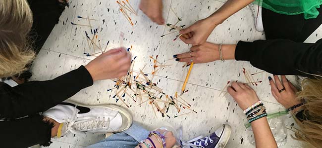 An image of students creating a bridge with household materials like toothpicks and marshmallows.